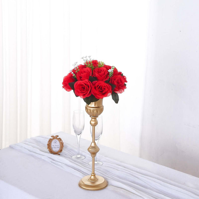 Gold candlestick with red rose bouquet on a table.