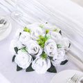 White artificial rose bouquet with green accents on a table setting.