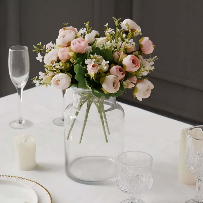 Artificial flower bouquet in a clear glass vase on a dining table.