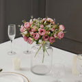 Pink rose bouquet in a clear vase on a dining table setting.
