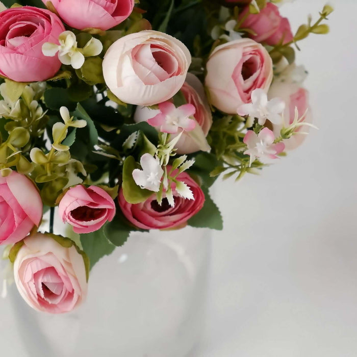 Pink and white artificial flower bouquet in a clear vase.