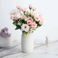Pink rose bouquet in a white vase on a marble surface.