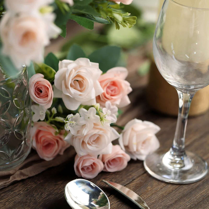 Elegant pink roses with glassware and silverware on a wooden table.