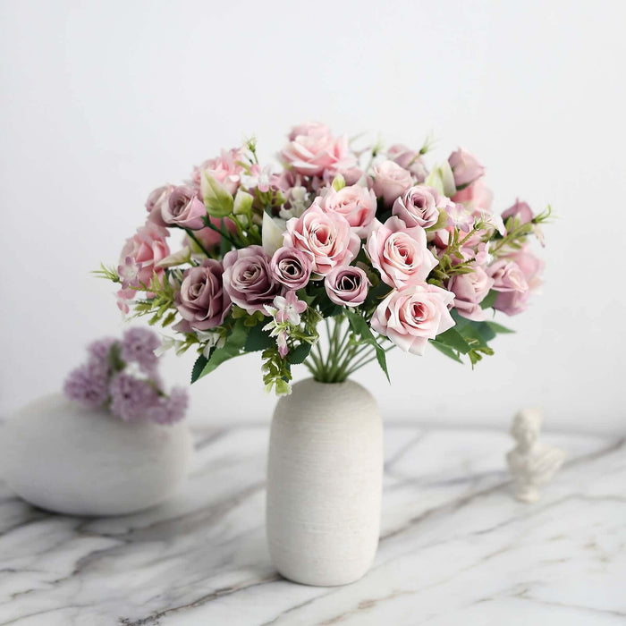 Pink and purple floral bouquet in a white vase on a marble surface.