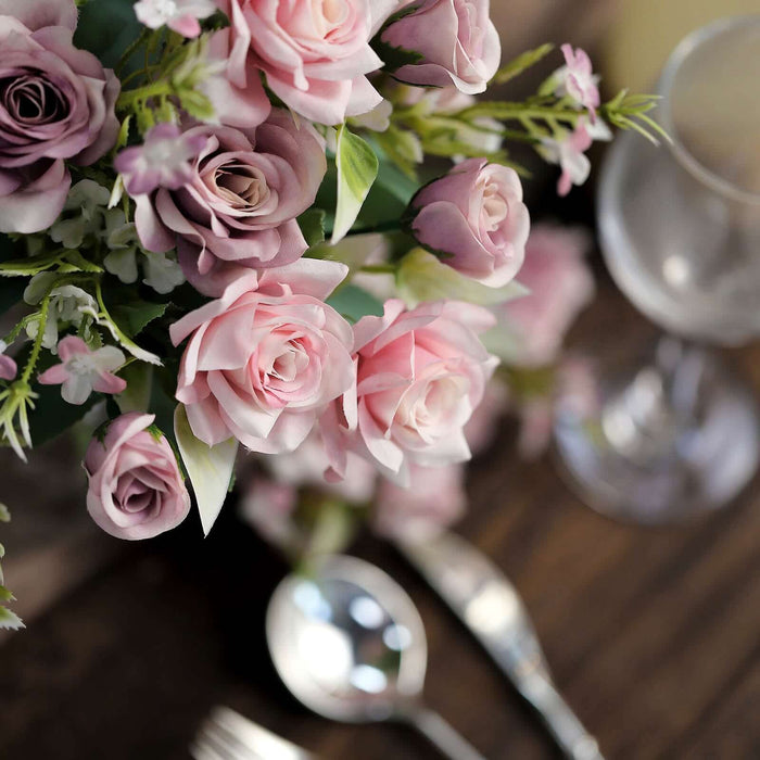 Artificial pink and purple roses in a decorative arrangement.