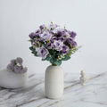 Purple rose bouquet in a minimalist vase on a marble surface.