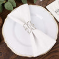 Elegant silver napkin holder on a white plate with a folded cloth napkin.