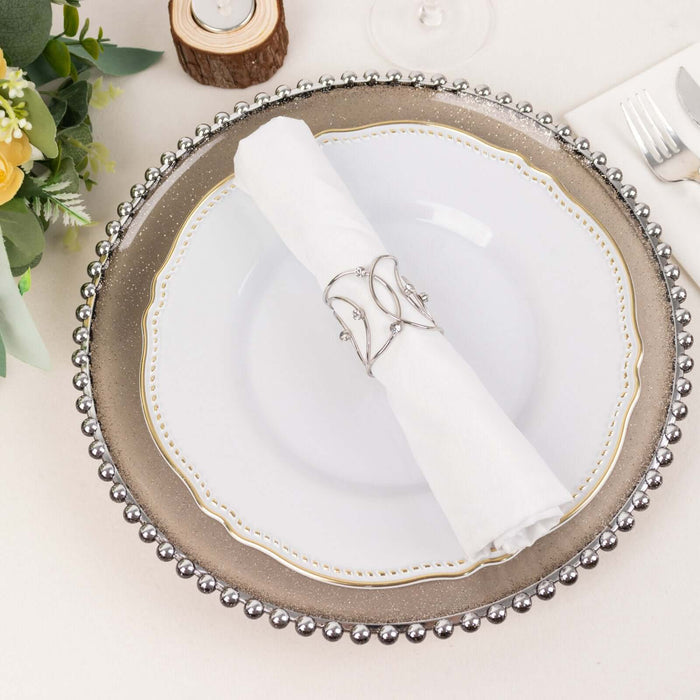 Elegant dinner plate with silver beaded charger and white napkin holder.