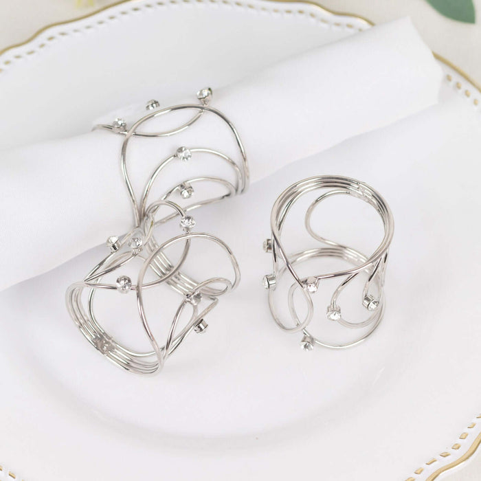Elegant silver napkin rings with rhinestones on a decorative plate.