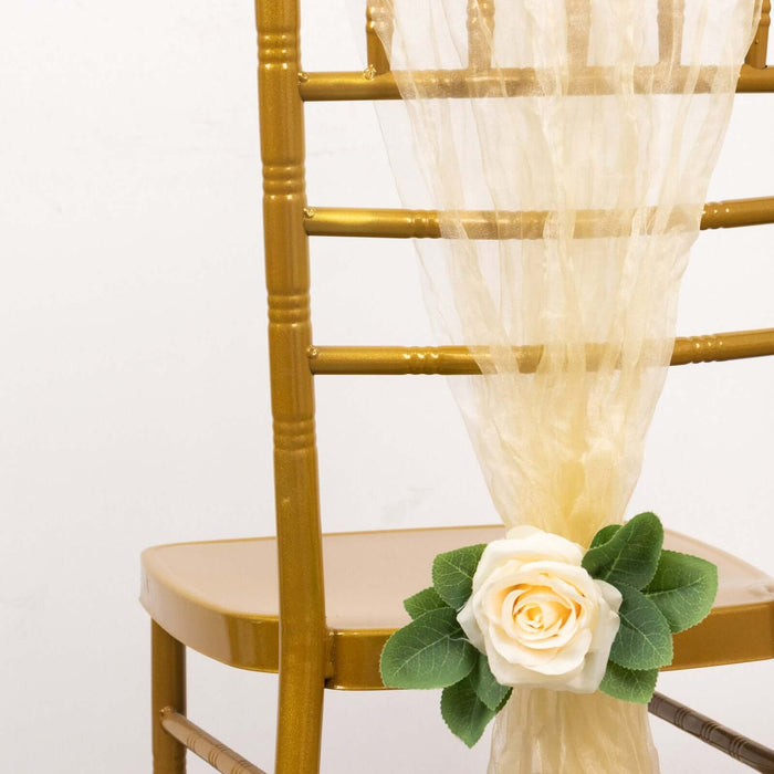 Gold chiavari chair adorned with a soft tulle drape and a white rose decoration.