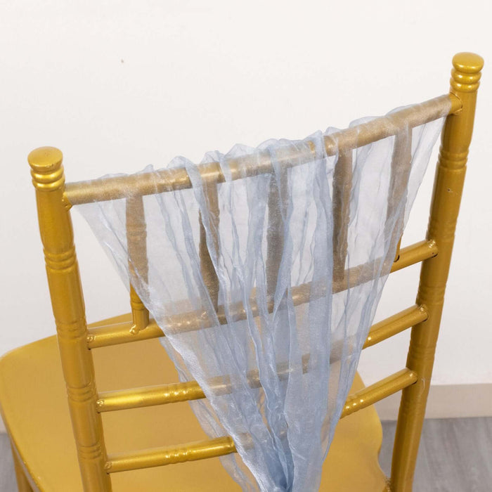 Gold chiavari chair with sheer blue fabric draping from the back.