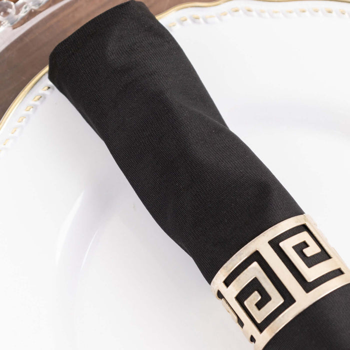Black napkin with gold geometric holder on a white plate