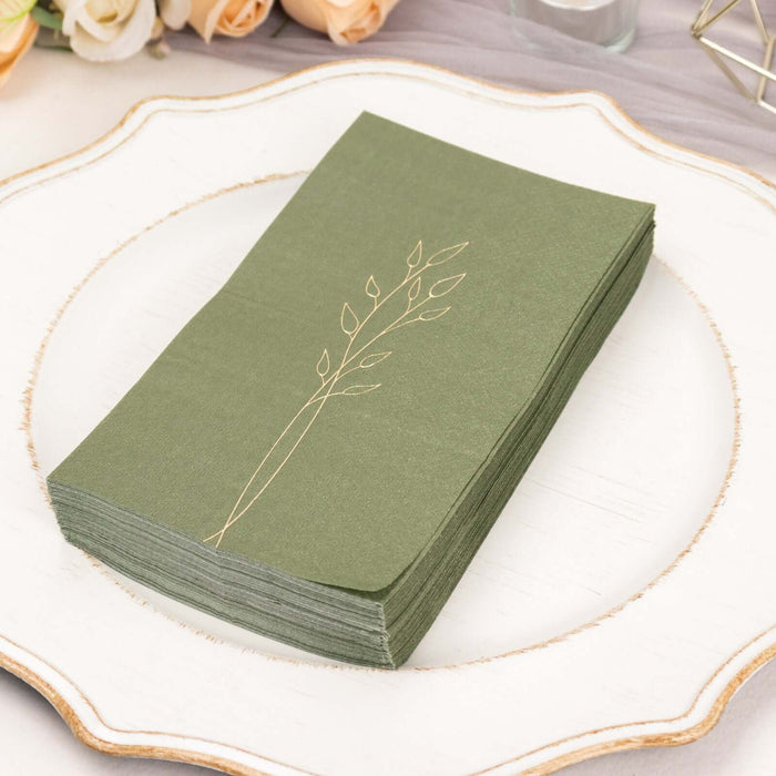 Green napkins with a gold leaf design displayed on a decorative plate.