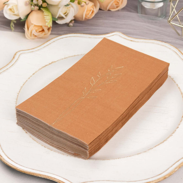 Elegant kraft paper napkins with gold leaf design on a decorative plate.