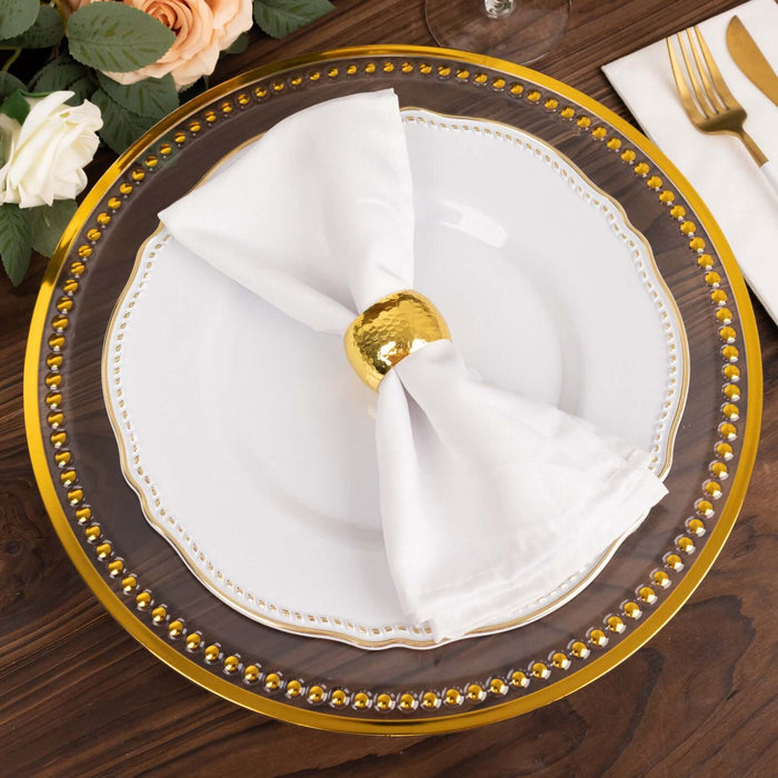 Elegant dinner plate with golden accents and a white napkin tied with a gold ring.