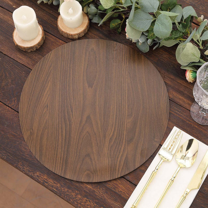 Wooden round placemat on a rustic table with candles and greenery.