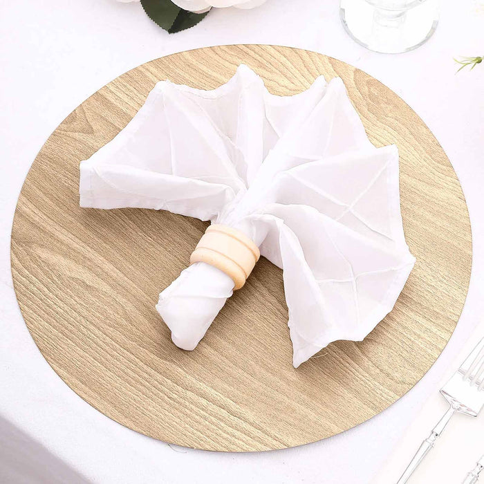 White napkin folded in an umbrella shape on a round wooden placemat.