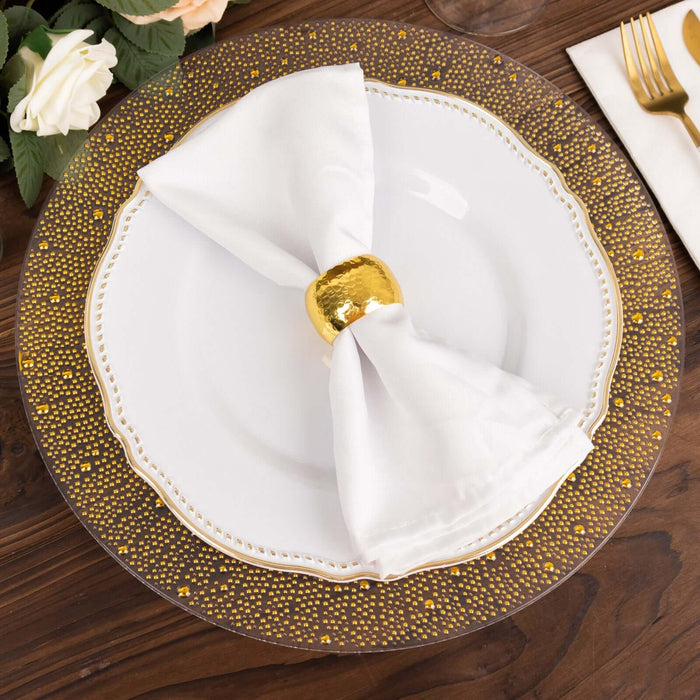 Elegant white plate with gold-accented napkin and holder on a wooden table.