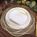 Elegant gold and white dinner plate set on a wooden table.