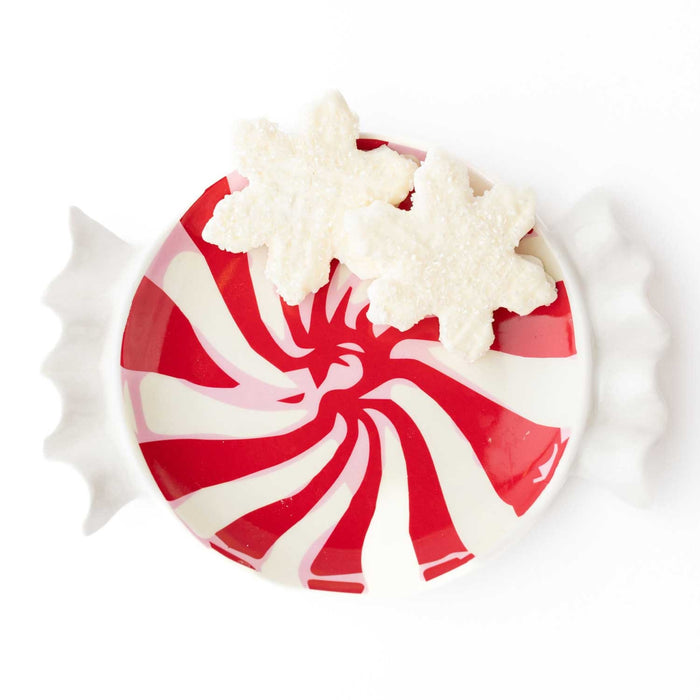 Red and white peppermint striped dessert plate topped with whipped cream, overhead view