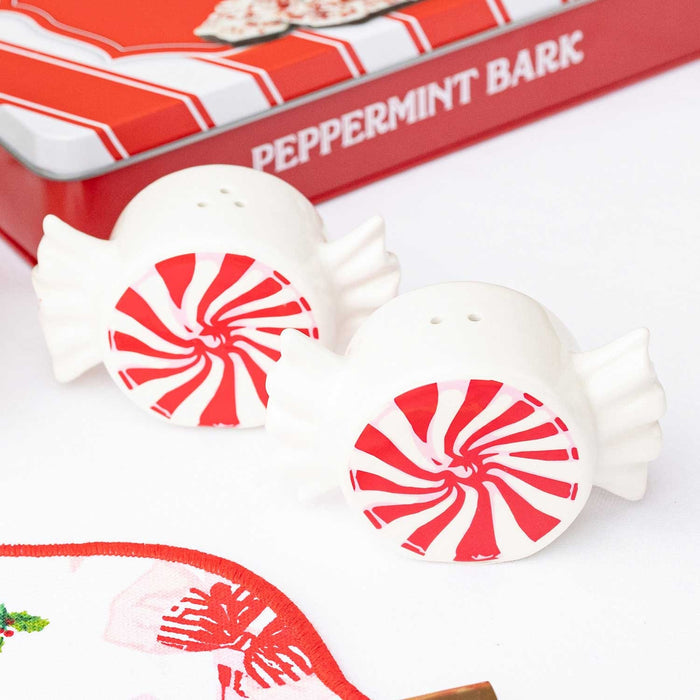 Two white ceramic peppermint-shaped salt and pepper shakers with red swirl design and packaging