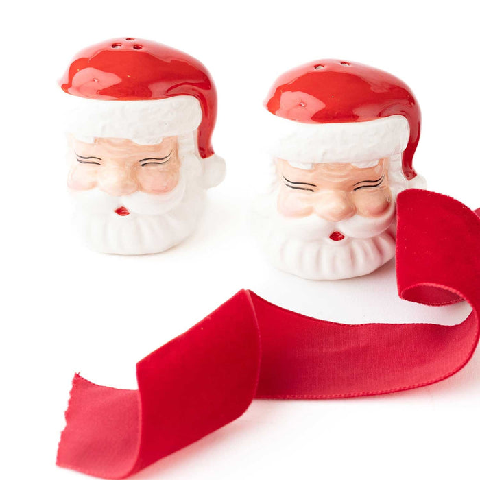 Red and white ceramic Santa Claus salt and pepper shaker set with festive ribbon on white background