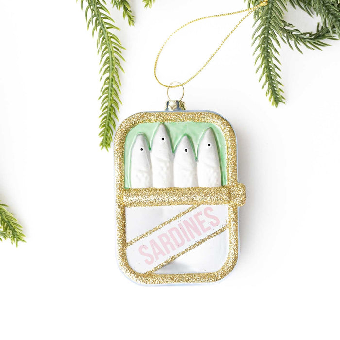 Gold glitter sardines can ornament with white ceramic sardines and pink text label on white background