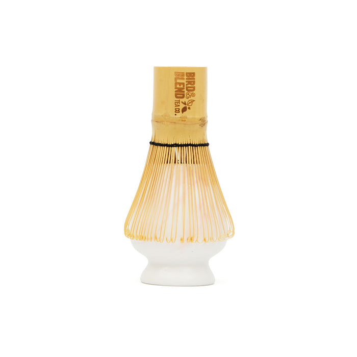 traditional bamboo matcha tea whisk on top of white and pink marbled matcha tea whisk holder