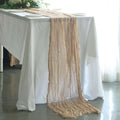 Table runner in soft beige draping elegantly over a white table.