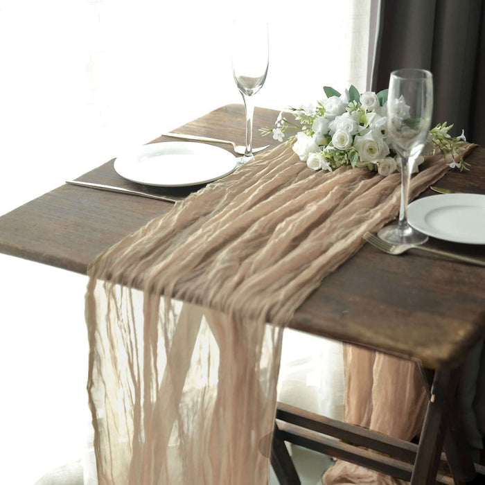 Elegant table setting with a textured runner, plates, and floral centerpiece.