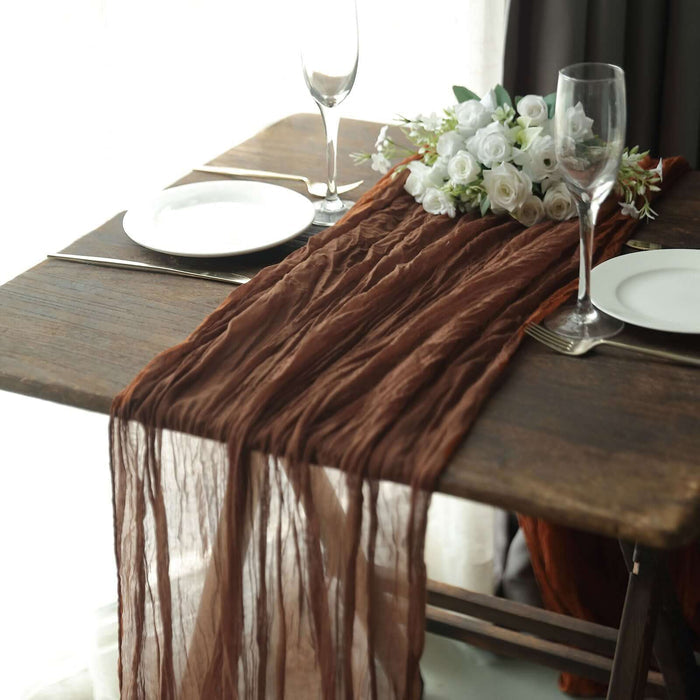 Elegant brown table runner on a rustic wooden table with floral arrangement.