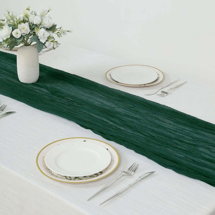 Green table runner on a white table setting with plates and cutlery.