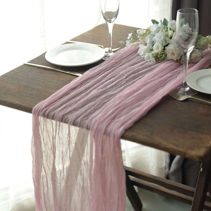 Pink table runner on a rustic wooden table with elegant dinnerware and floral decor.