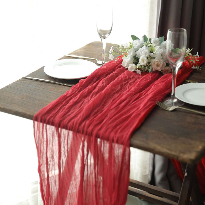 Red table runner with floral centerpiece set on a wooden table.