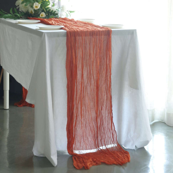Orange textured table runner draped over a white tablecloth.