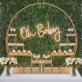 Baby shower dessert display with "Oh Baby" neon sign and floral accents.