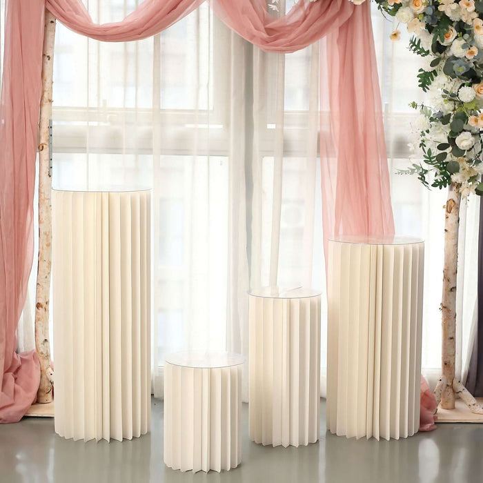 Elegant white pedestal tables in a decorative setting with soft drapes and flowers.