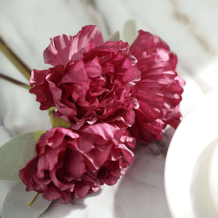 Artificial peony flowers in deep pink, elegantly arranged on a marble surface.