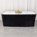 Black sequin tablecloth draped over a rectangular table with floral centerpiece.