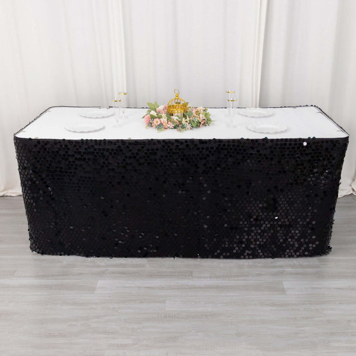 Black sequin tablecloth draped over a rectangular table with floral centerpiece.