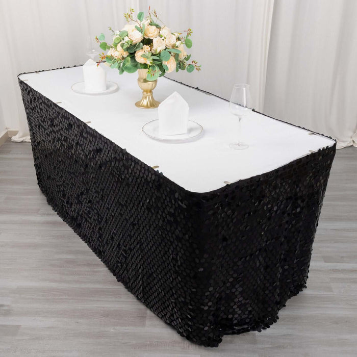 Black sequin tablecloth draped over a table with floral centerpiece and glassware.