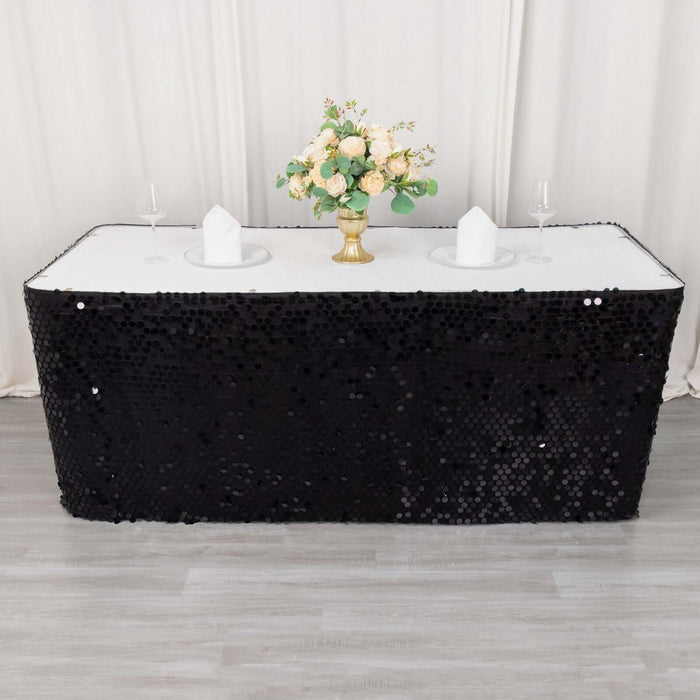 Black sequin table cover with floral centerpiece and elegant table setting.