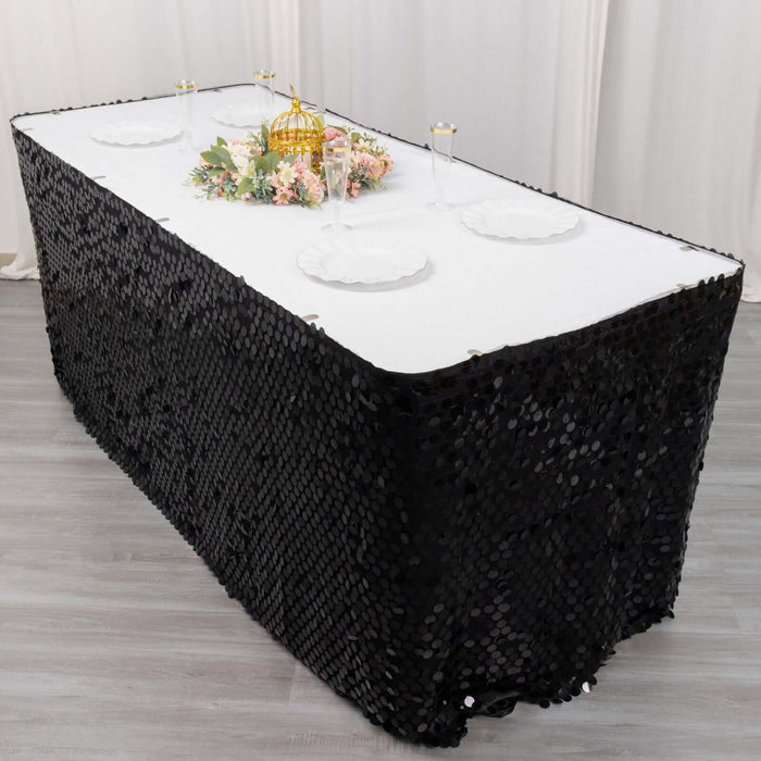 Black sequin tablecloth draped over a rectangular table with floral centerpiece.