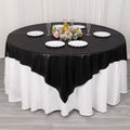 Round black and white tablecloth with floral centerpiece and dinnerware.