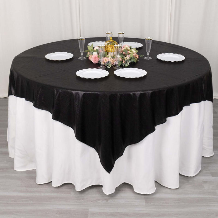 Round black and white tablecloth with floral centerpiece and dinnerware.