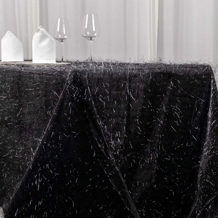 Black tablecloth with silver threads, styled with glasses and decorative items.