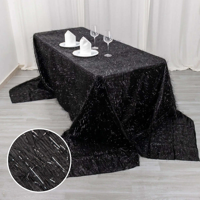 Black shimmering tablecloth draped over a table with glassware and napkins.
