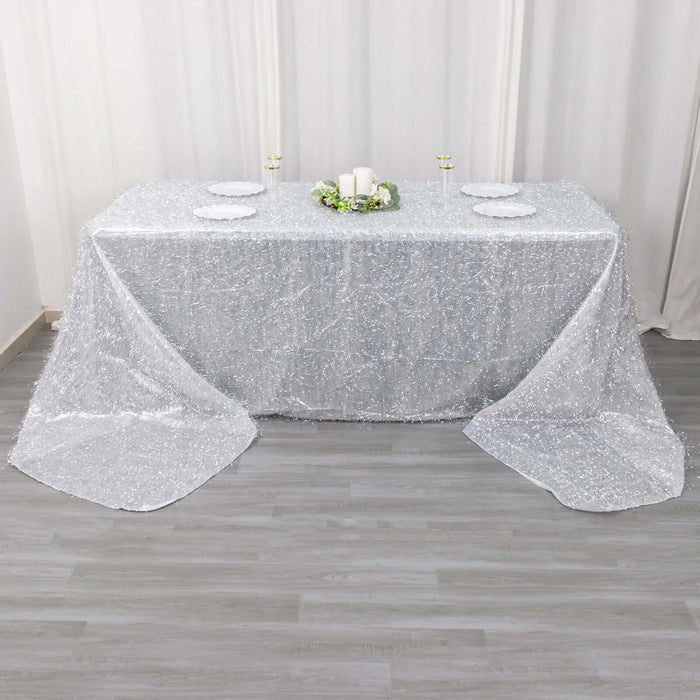 Sparkling silver tablecloth draped over a table with decorative plates and candles.