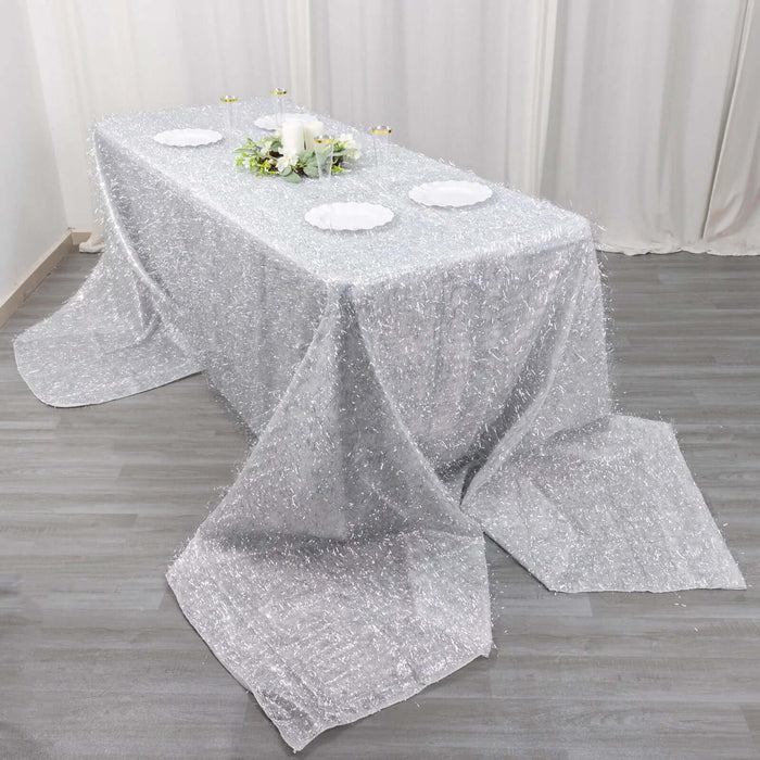 Sparkling silver tablecloth draped over a dining table with decorative plates.