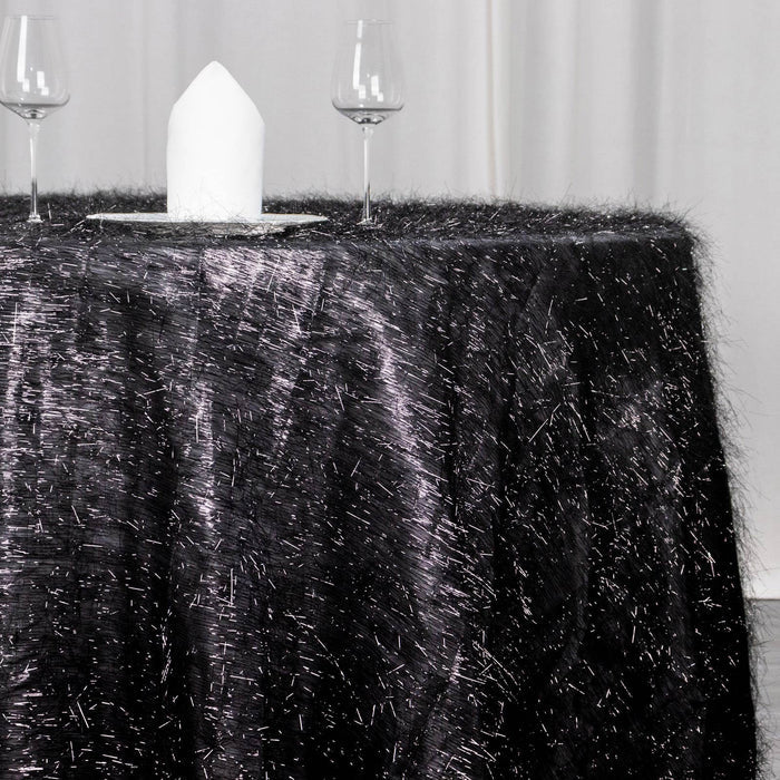 Black tablecloth with textured fibers, set with glassware and a napkin.